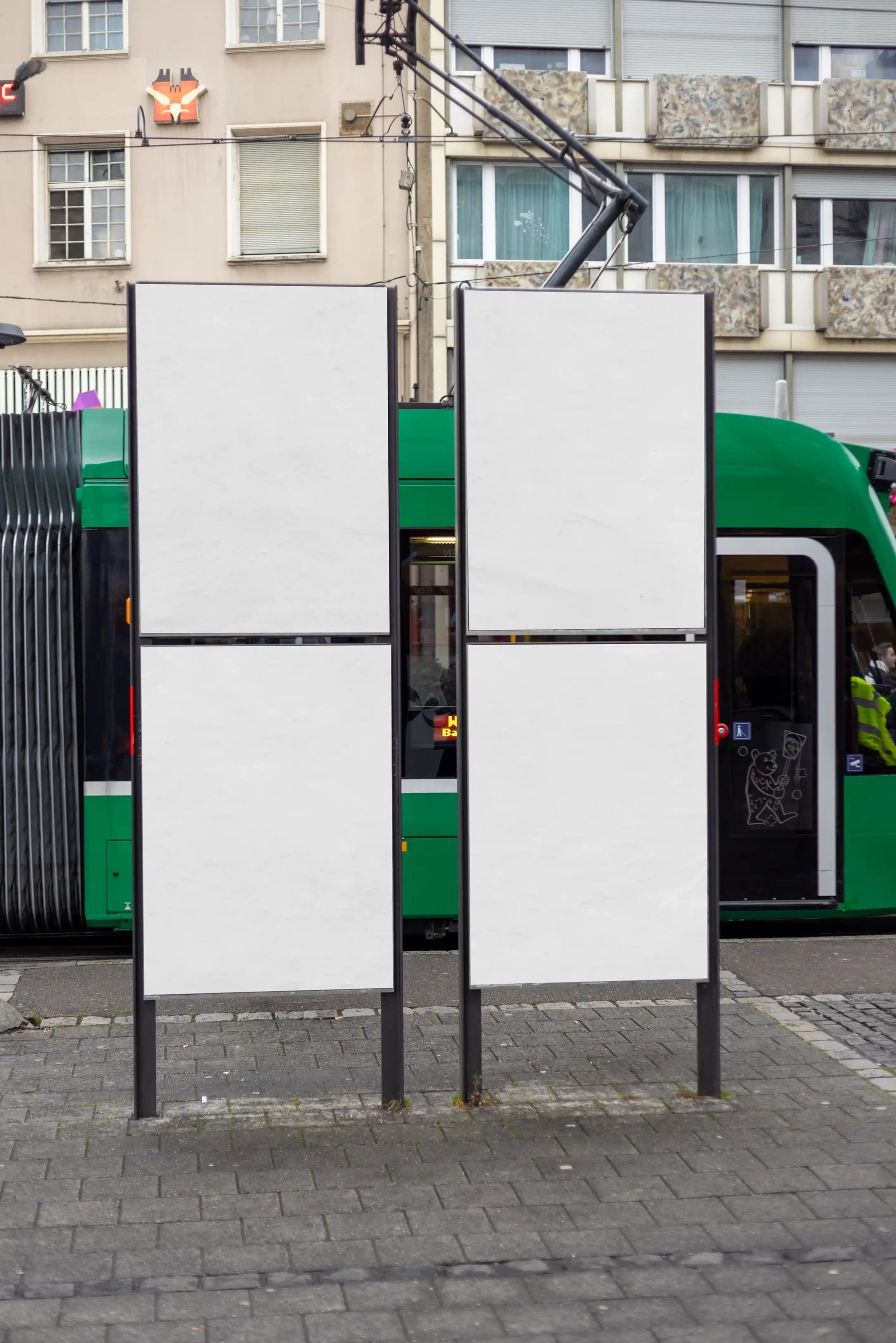 Four poster display mockup at Basel Claraplatz – JM307 Four blank vertical poster panels at Basel Claraplatz with a tram and city street in the background